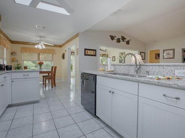 kitchen featuring lofted ceiling with skylight, dishwasher, sink, ceiling fan, and white cabinets