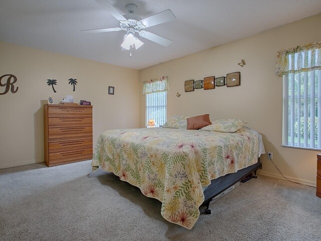 bedroom with ceiling fan, carpet floors, and multiple windows