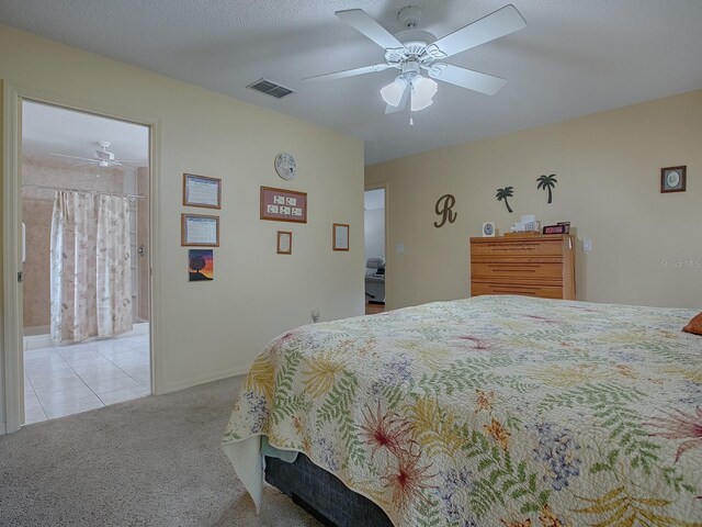 bedroom with a textured ceiling, light colored carpet, ceiling fan, and ensuite bathroom