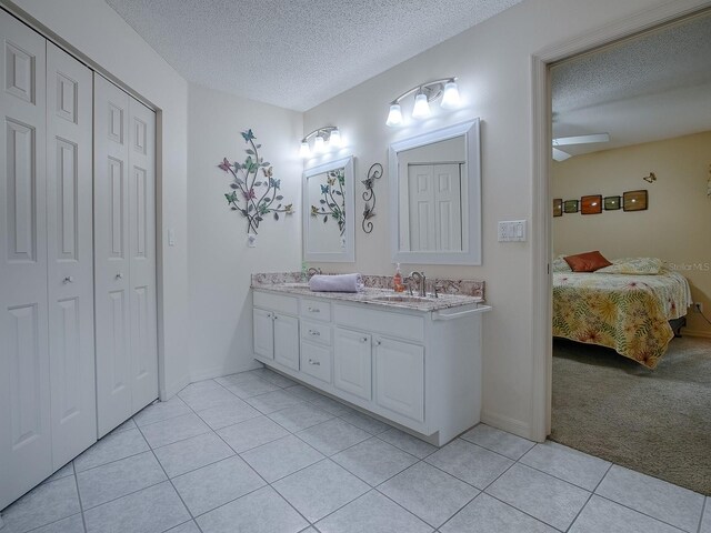 bathroom featuring a textured ceiling, vanity, ceiling fan, and tile patterned flooring