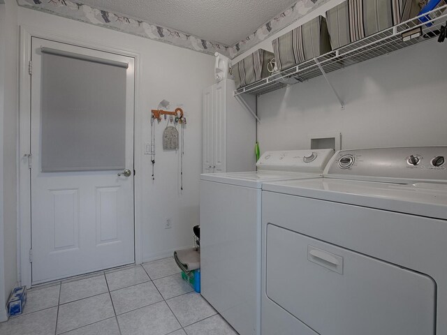 laundry area with light tile patterned floors, a textured ceiling, and washer and clothes dryer