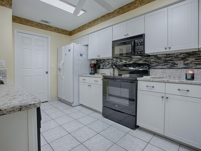 kitchen featuring black appliances, white cabinetry, light tile patterned floors, and tasteful backsplash