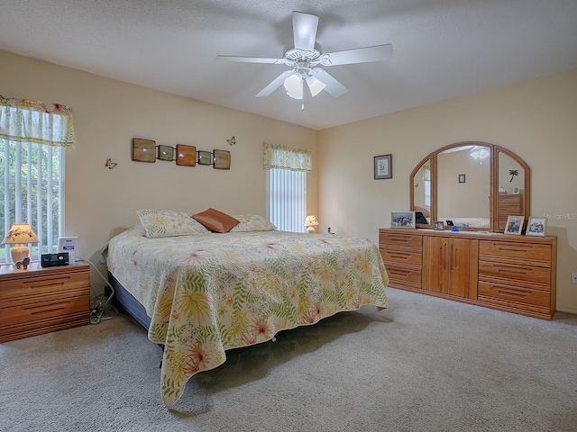 bedroom featuring light carpet, a textured ceiling, and ceiling fan