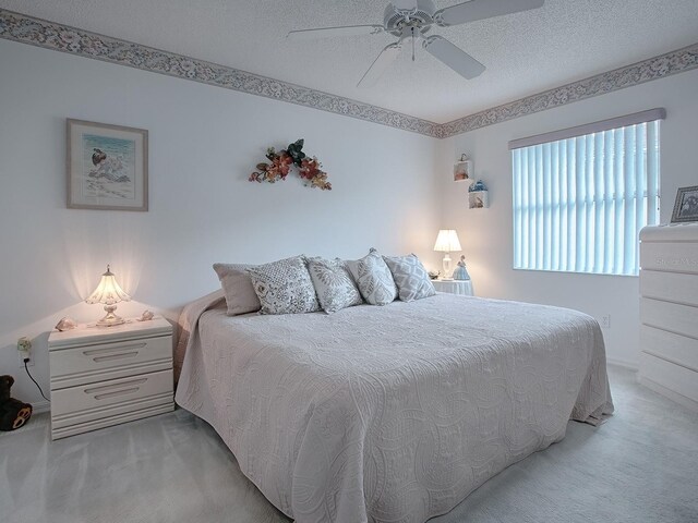 carpeted bedroom with a textured ceiling and ceiling fan