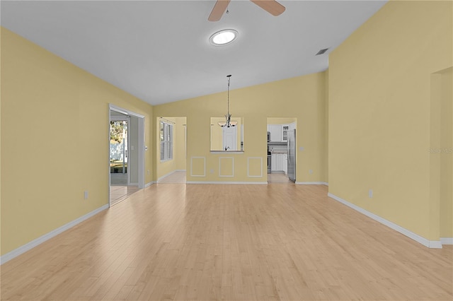 unfurnished living room with lofted ceiling, light wood-type flooring, and ceiling fan with notable chandelier