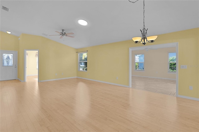 unfurnished room featuring vaulted ceiling, a wealth of natural light, ceiling fan with notable chandelier, and light wood-type flooring