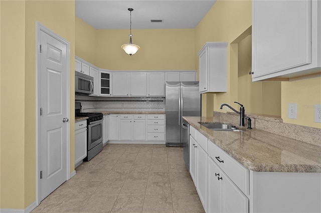 kitchen featuring light stone countertops, stainless steel appliances, sink, decorative light fixtures, and white cabinets