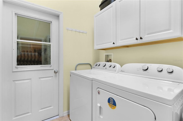 clothes washing area with washing machine and clothes dryer and cabinets