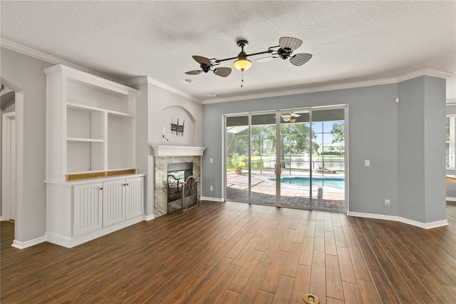 unfurnished living room with a high end fireplace, a textured ceiling, crown molding, ceiling fan, and dark hardwood / wood-style floors