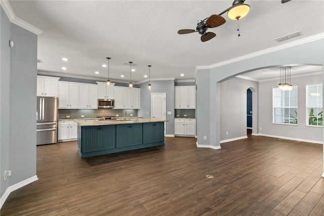 kitchen featuring appliances with stainless steel finishes, white cabinetry, ceiling fan with notable chandelier, a kitchen island with sink, and dark hardwood / wood-style floors