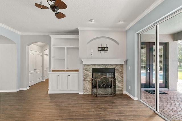 unfurnished living room featuring ceiling fan, a textured ceiling, dark wood-type flooring, and a high end fireplace