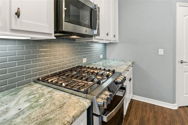 kitchen featuring light stone countertops, stainless steel appliances, dark wood-type flooring, and white cabinetry