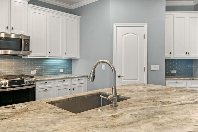 kitchen with ornamental molding, white cabinetry, sink, and stainless steel appliances