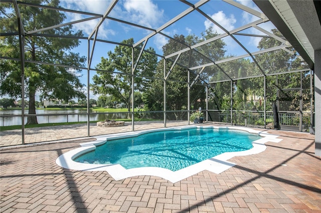 view of pool with a patio, glass enclosure, and a water view