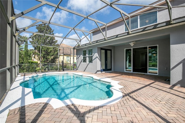 view of swimming pool with ceiling fan, glass enclosure, and a patio area