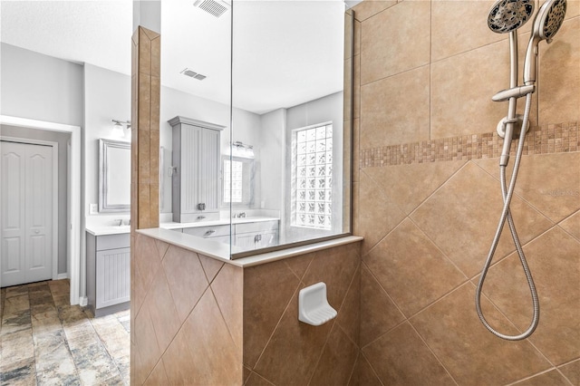 bathroom featuring a tile shower and vanity