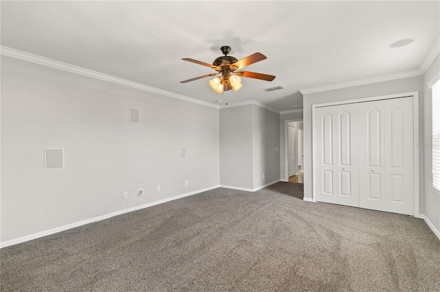 unfurnished bedroom featuring ceiling fan, a closet, crown molding, and dark colored carpet