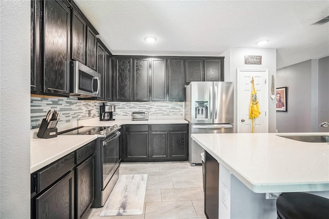 kitchen with decorative backsplash, stainless steel appliances, light tile patterned flooring, and sink