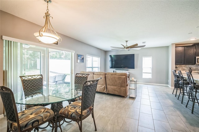 dining room with a textured ceiling, light tile patterned flooring, and ceiling fan