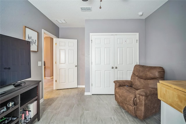 living area with ceiling fan and a textured ceiling