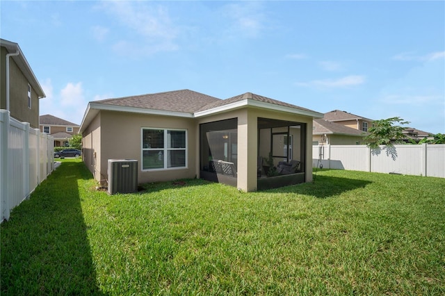 back of property with central AC unit, a sunroom, and a yard