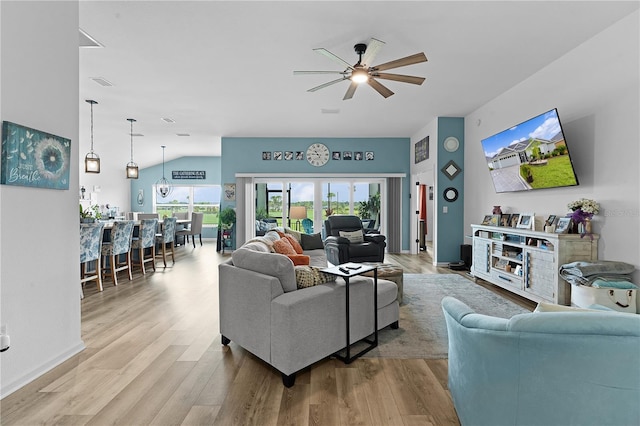 living room with light hardwood / wood-style floors, ceiling fan, and vaulted ceiling