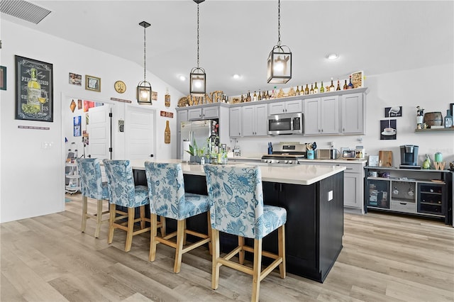 kitchen featuring gray cabinets, stainless steel appliances, and a center island with sink