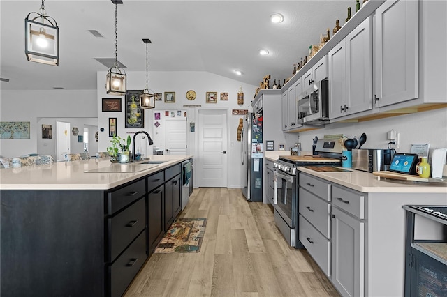 kitchen featuring appliances with stainless steel finishes, light wood-type flooring, lofted ceiling, pendant lighting, and sink