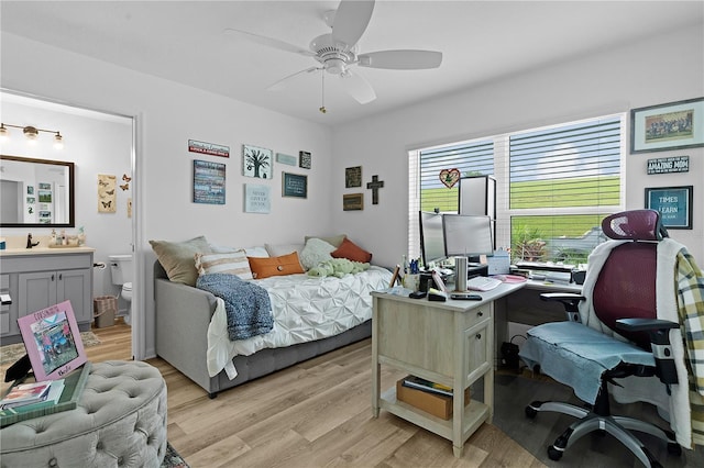 bedroom with light wood-type flooring, ceiling fan, ensuite bathroom, and sink