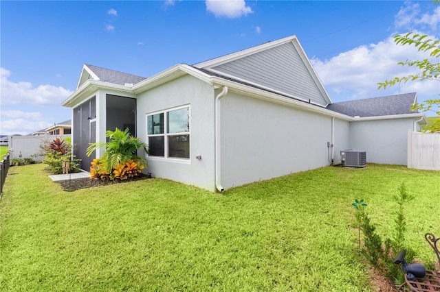 rear view of property with central AC, a lawn, and a sunroom