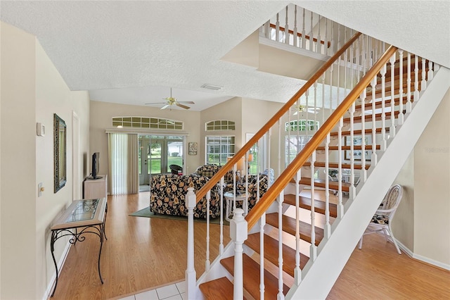 stairway featuring a textured ceiling, wood finished floors, a ceiling fan, and vaulted ceiling