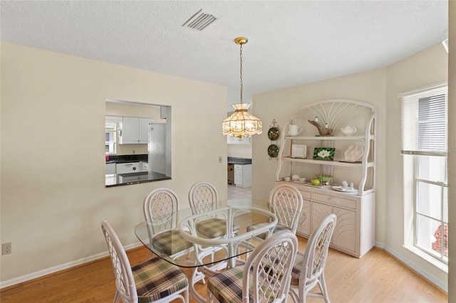 dining area with a wealth of natural light, visible vents, and light wood-style floors