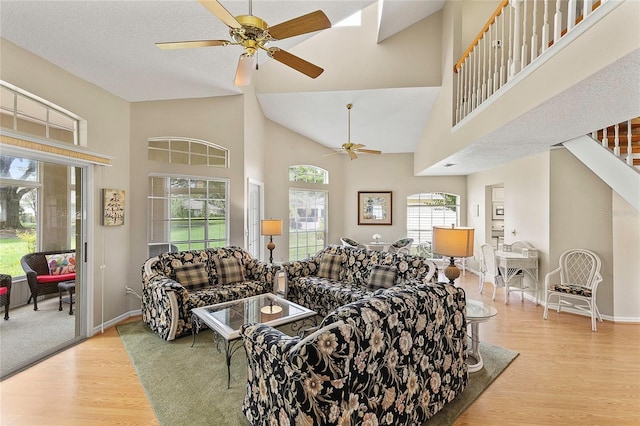 living room featuring baseboards, a high ceiling, a ceiling fan, and wood finished floors