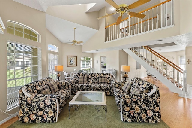 living area with stairs, high vaulted ceiling, wood finished floors, and a ceiling fan