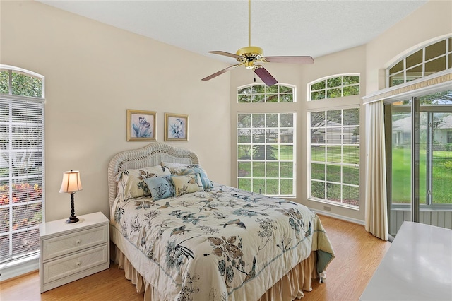 bedroom with light wood-type flooring, a textured ceiling, and ceiling fan