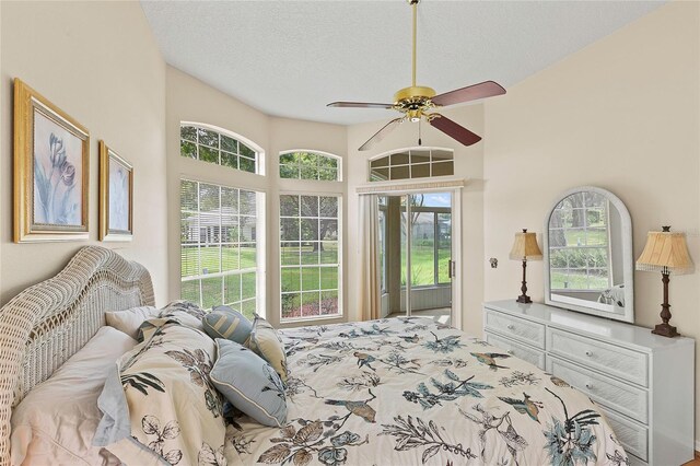 bedroom with a towering ceiling, multiple windows, ceiling fan, and a textured ceiling