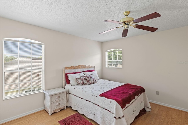 bedroom featuring a textured ceiling, ceiling fan, and light hardwood / wood-style floors