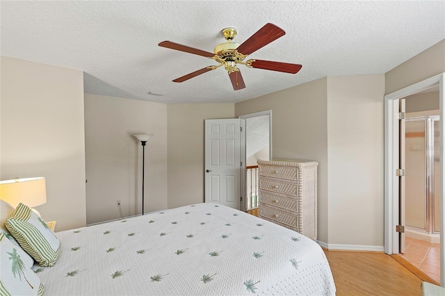 bedroom featuring light wood-type flooring, baseboards, a textured ceiling, and a ceiling fan