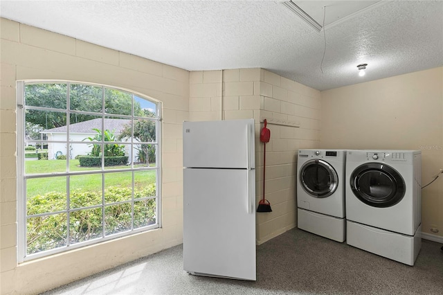 clothes washing area with a textured ceiling, a wealth of natural light, and washer and dryer