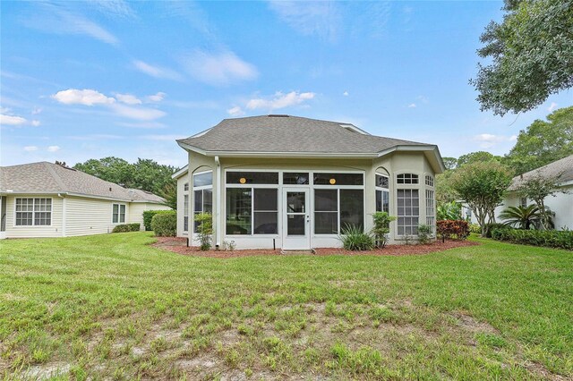 rear view of house with a yard and a sunroom