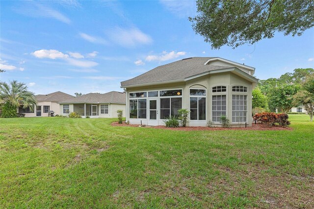 back of property with a yard and a sunroom