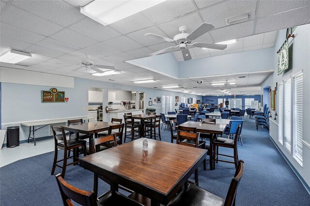 carpeted dining space featuring a paneled ceiling and ceiling fan