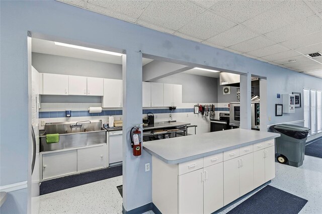 kitchen with a paneled ceiling, sink, and white cabinetry