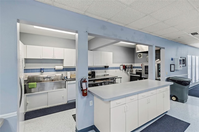 kitchen with visible vents, speckled floor, a sink, light countertops, and white cabinets