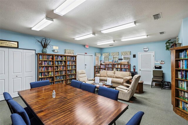 carpeted dining room with a textured ceiling