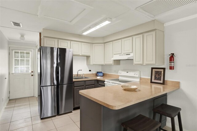 kitchen with sink, stainless steel fridge, electric stove, kitchen peninsula, and a kitchen bar