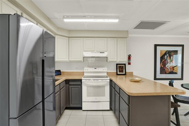 kitchen featuring stainless steel refrigerator, white cabinetry, white electric stove, kitchen peninsula, and a breakfast bar area