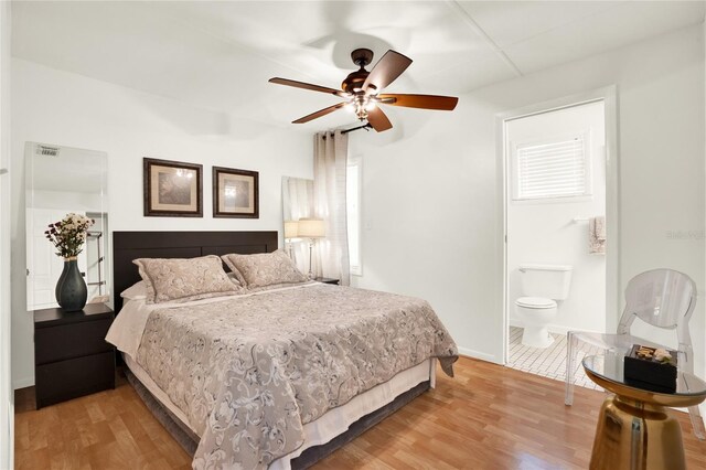 bedroom featuring light wood-type flooring, multiple windows, ceiling fan, and ensuite bathroom