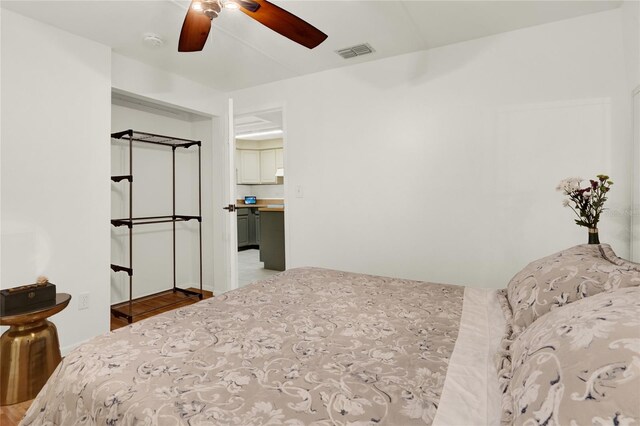 bedroom featuring hardwood / wood-style floors, ensuite bathroom, and ceiling fan