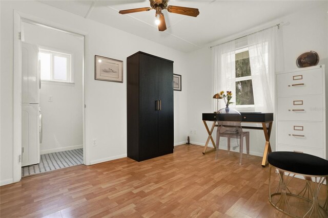 misc room featuring ceiling fan, stacked washer and dryer, and light hardwood / wood-style floors